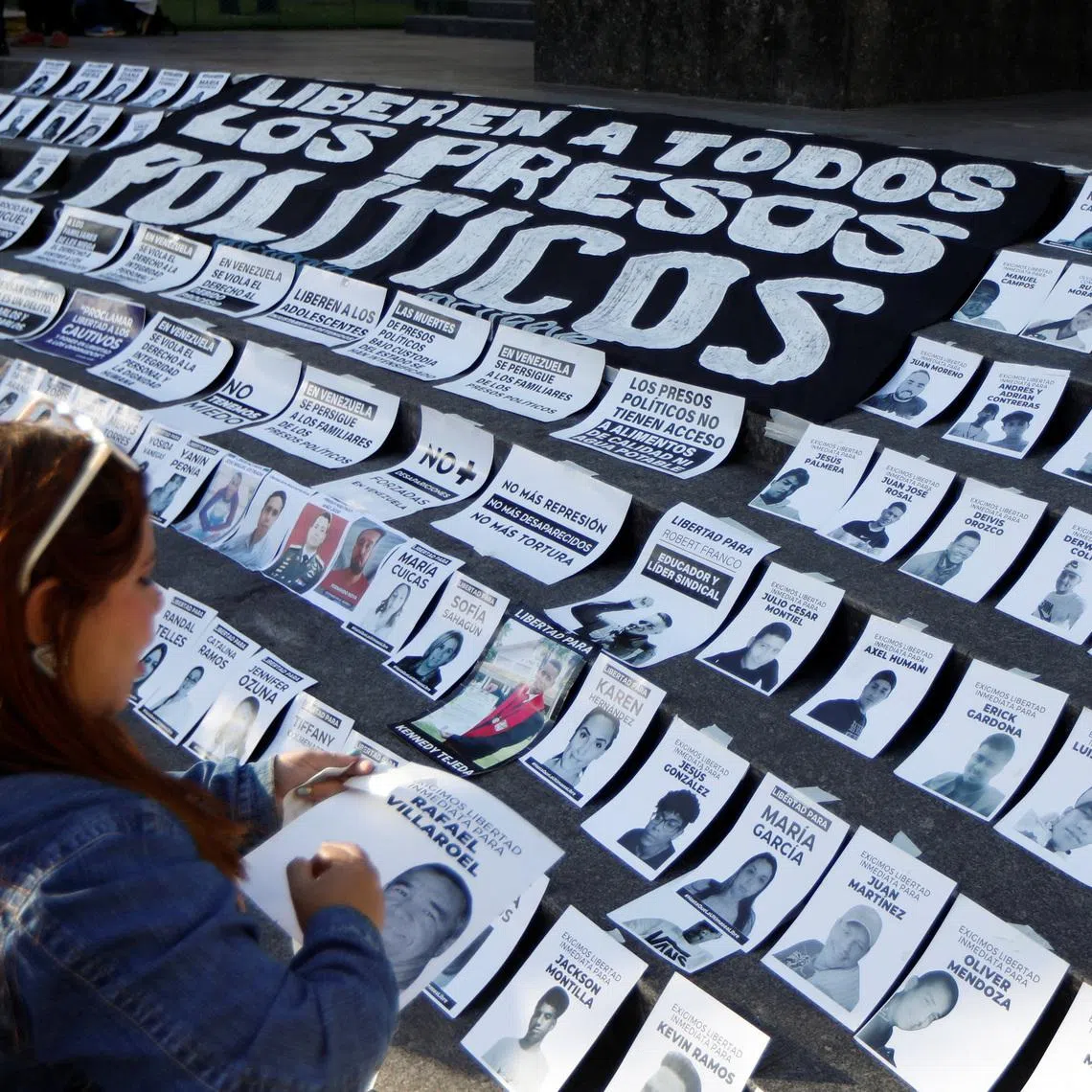 A woman arranges photographs of political prisoners during a protest called “Christmas Without Political Prisoners,” demanding their release after the disputed 2024 presidential elections as U.S. President Donald Trump’s administration increases pressure on Nicolas Maduro’s government, in Caracas, Venezuela, December 14, 2025. REUTERS/Leonardo Fernandez Viloria
