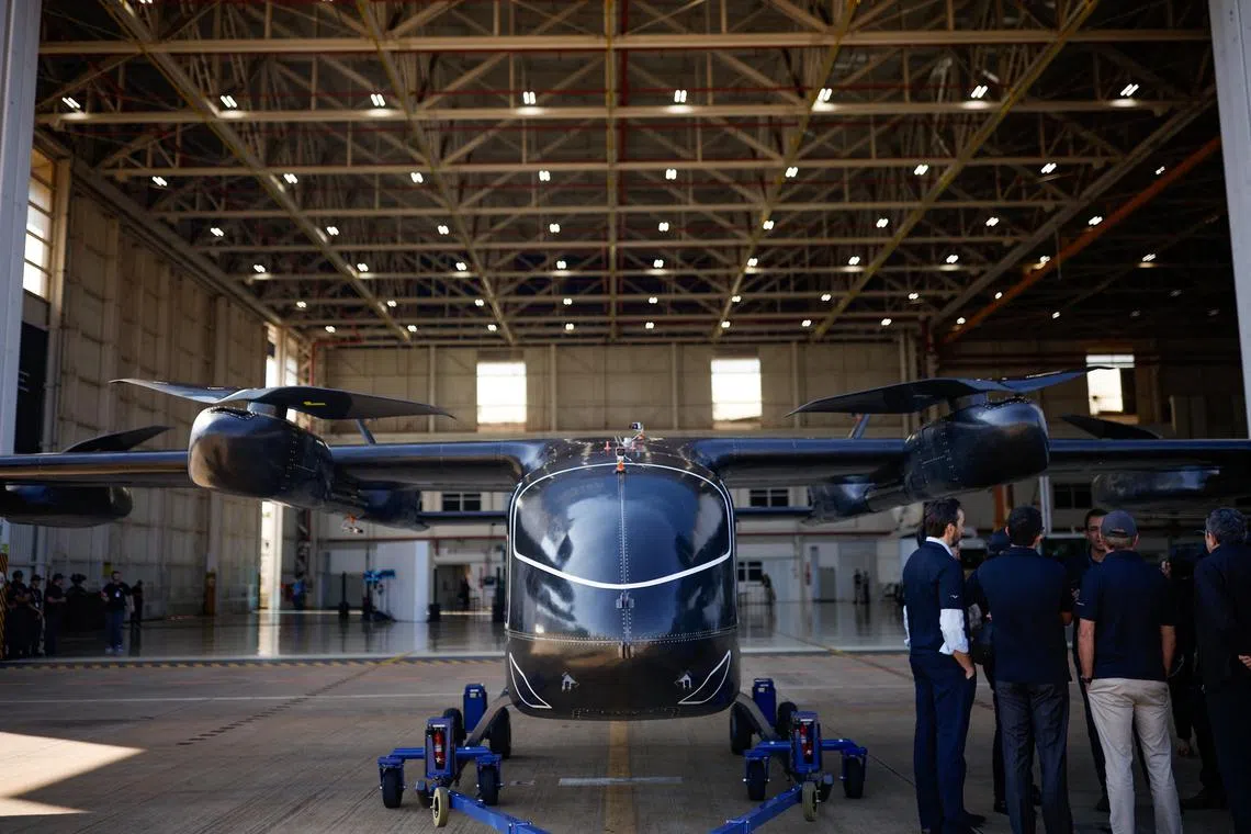 People stand near the full-scale prototype of electric vertical take-off and landing (eVTOL) aircraft developed by Eve Air Mobility, an Embraer group company, as it is presented for the first time in Gaviao Peixoto, Brazil July 3, 2024. REUTERS/Amanda Perobelli