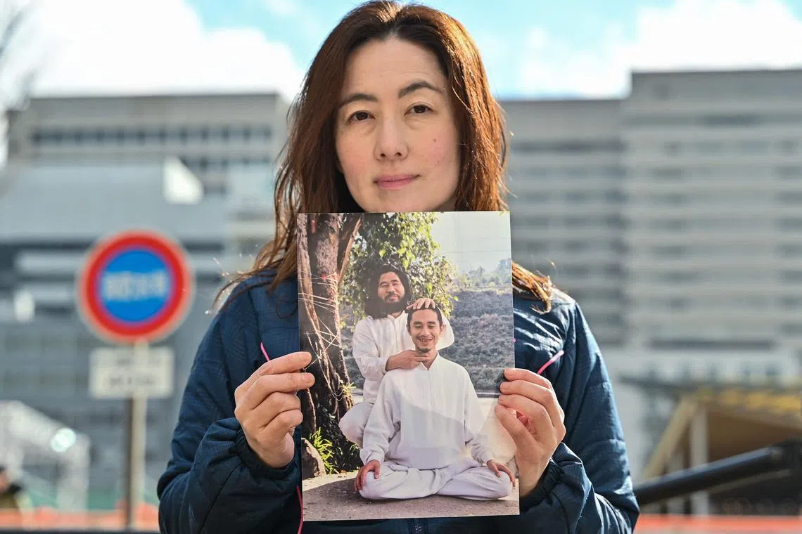 Yuki Niimi, the widow of Tomomitsu Niimi, with a photo of her husband (front) with cult leader Shoko Asahara.
