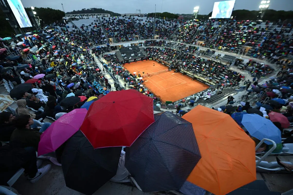 Spectators in the Central Court protecting themselves as the rain interrupts the third round of the Men's ATP Rome Open tennis tournament between Greece's Stefanos Tsitsipas and Italy's Lorenzo Sonego at Foro Italico in Rome on May 15.