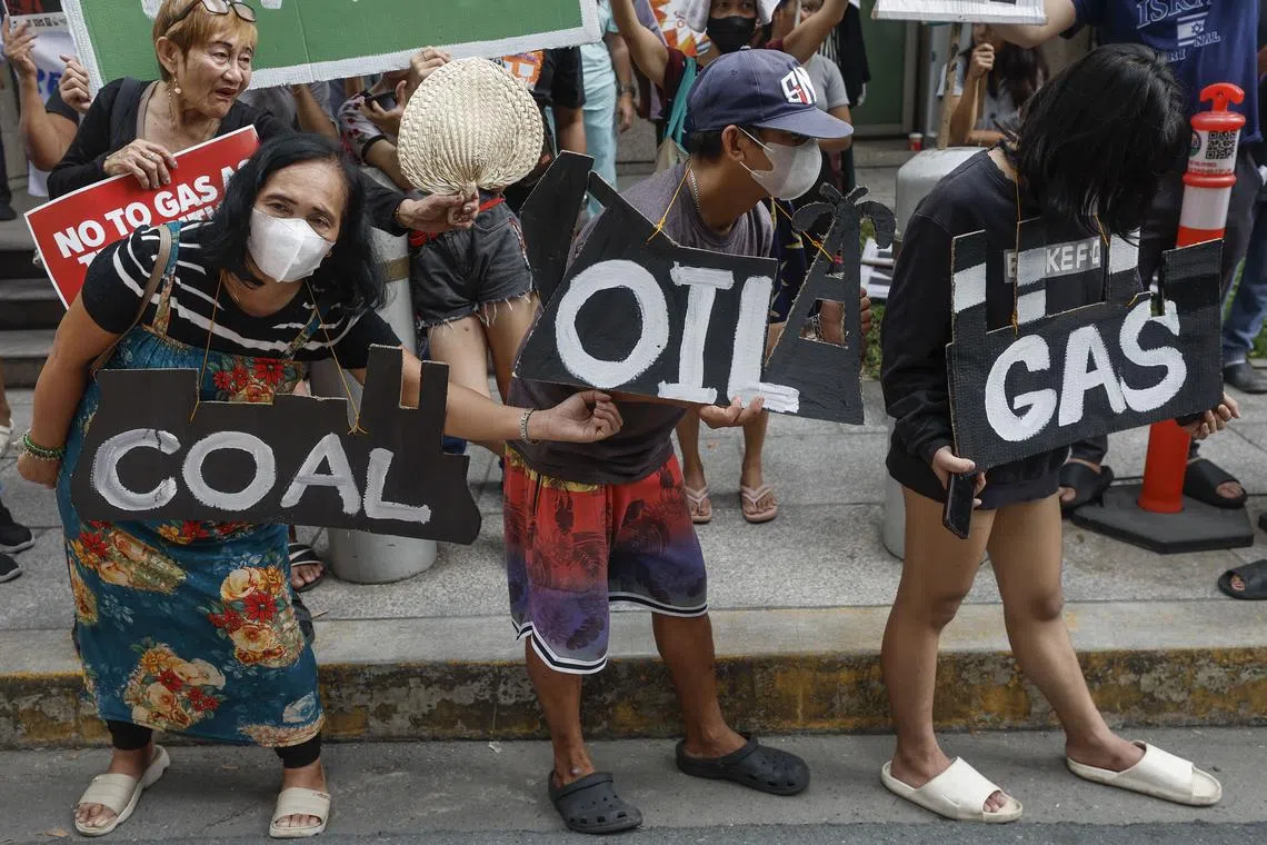 Protesters hold signs in opposition to fossil fuels as energy sources during a rally outside the Asian Development Bank in Metro Manila.