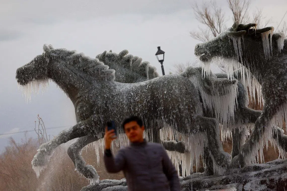A man takes a selfie at the "Los Indomables" monument with frozen water during a day of low temperatures, in Ciudad Juarez, Mexico January 8, 2025. REUTERS/Jose Luis Gonzalez TPX IMAGES OF THE DAY