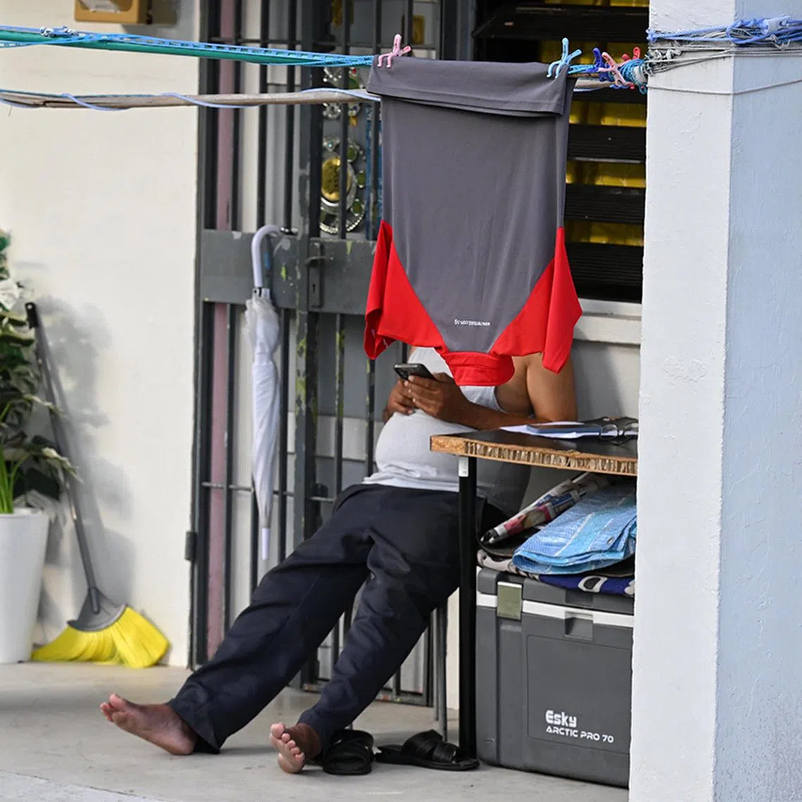 Generic photo of a man using his mobile phone while a polo t-shirt is hung out to dry at 45 Stirling Road on March 6, 2025.