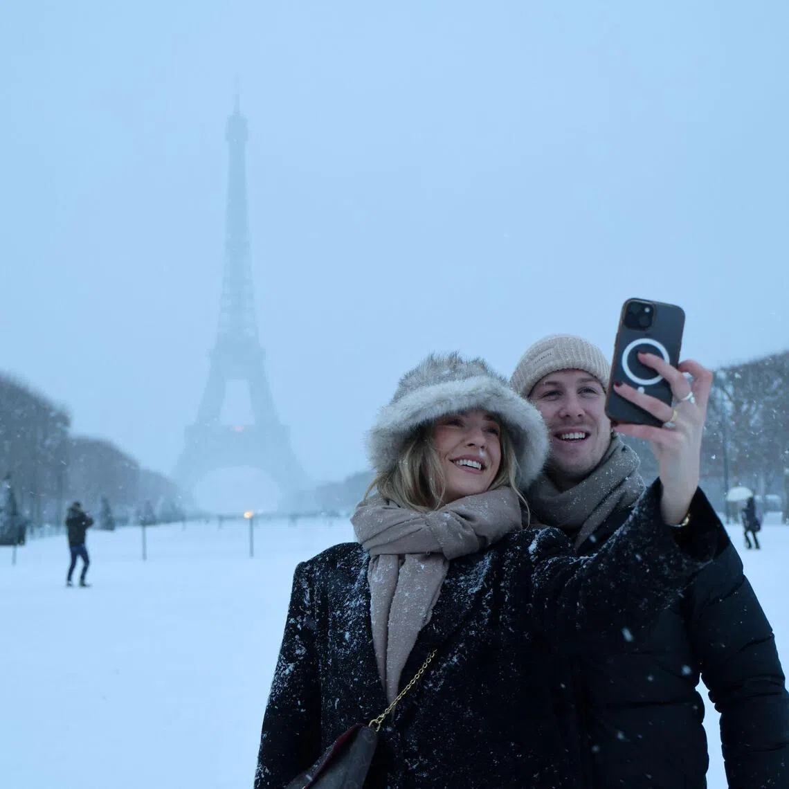 A couple takes a selfie in front of the Eiffel Tower in Paris.