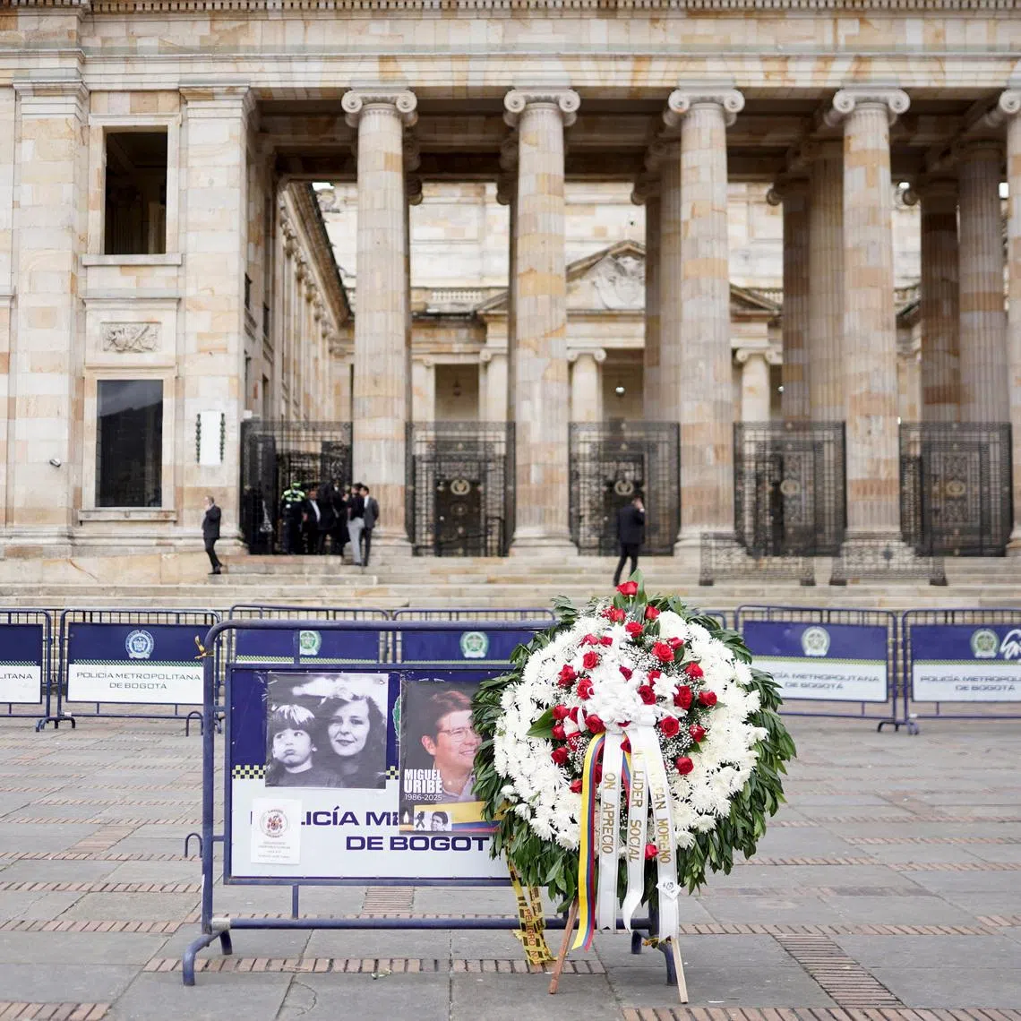 A wreath of flowers sits next to a barrier with images of Colombian Senator Miguel Uribe Turbay, who died two months after he was shot in the head at a campaign event, as his coffin rests at the Colombian congress, in Bogota, Colombia, August 13, 2025. REUTERS/Sergio Acero Yate
