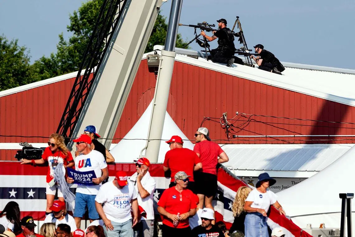 Law enforcement agents and members of the audience react after gunshots were fired at a campaign rally for former President Donald Trump.