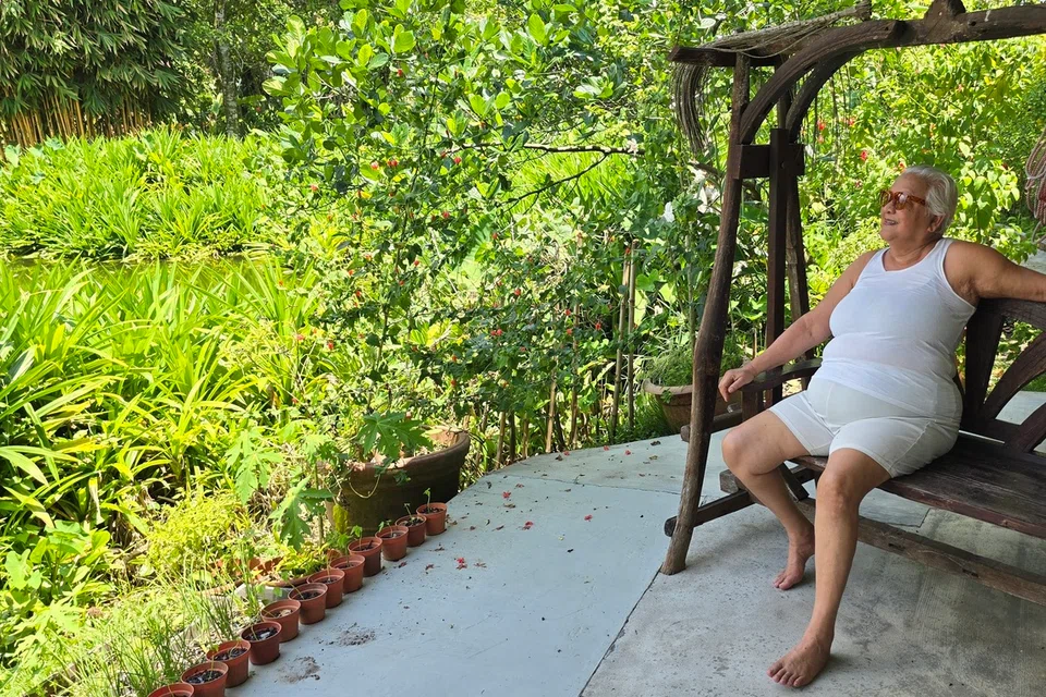 Mrs Ivy sits on her wooden porch swing, looking at the pond behind her house, both of which will be bulldozed after her lease ends in December 2026.