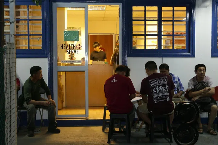 Foreign workers waiting to see a doctor at HealthServe’s Geylang clinic. The workers pay $5 a visit.