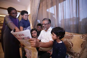 A grandfather reading Tamil Murasu with his grandchildren. 