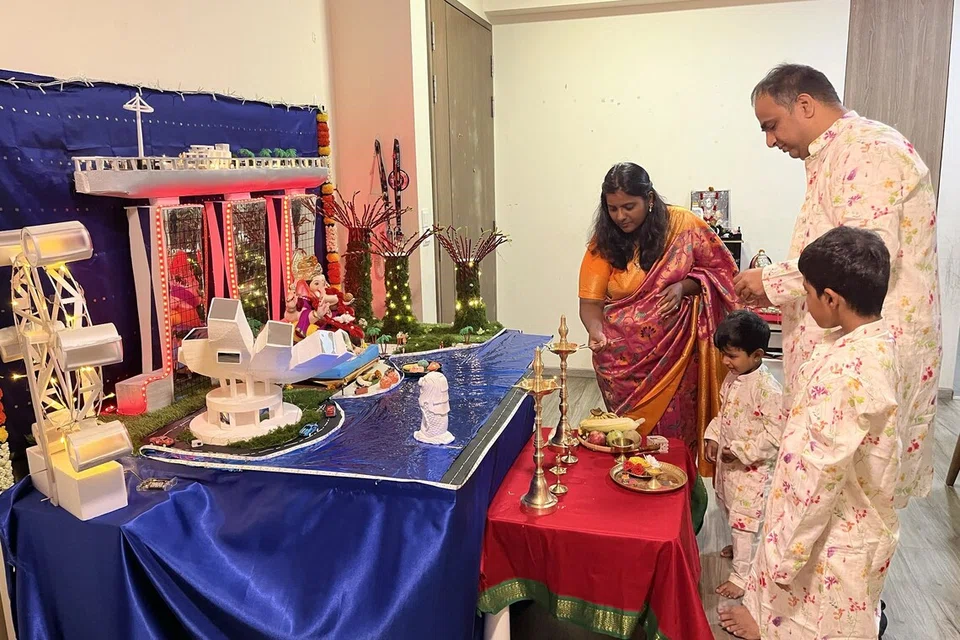 The Patil family performing a pooja at their altar with Singapore-themed decor as part of their Ganesh Chaturthi celebrations.