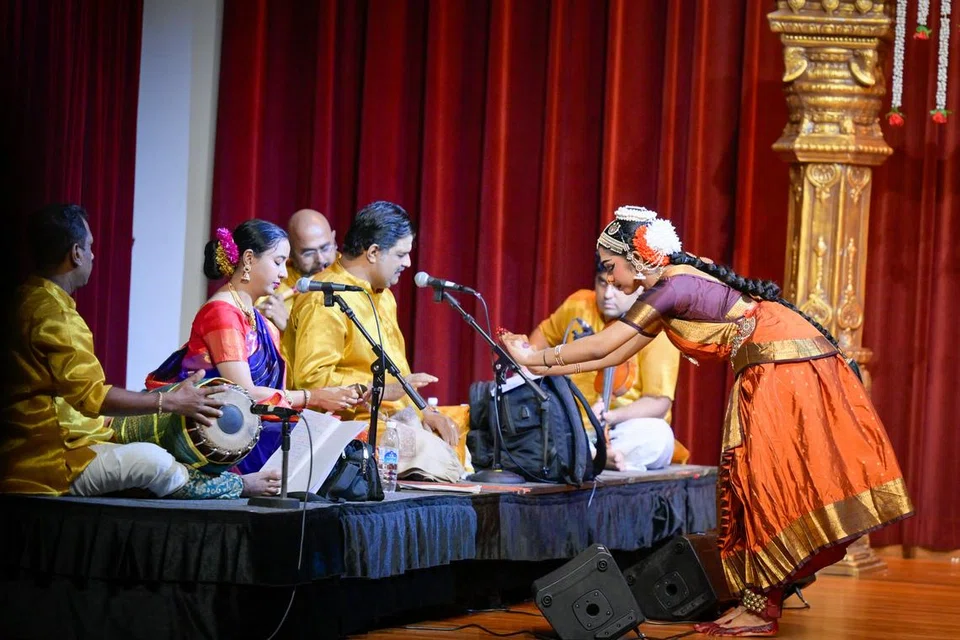 Ms Shruthika Kumar seeking blessings of the musical ensemble, which includes her guru Mrs Abiramy Kalaiselvan (in red and blue saree), at the start of her arangetram.