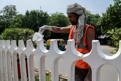 A worker painting a fence near the summit venue in New Delhi.