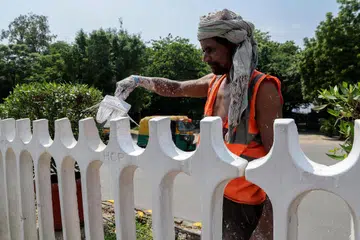 A worker painting a fence near the summit venue in New Delhi.