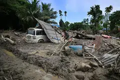A man searches for belongings amid the remains of his house, washed away by flash floods owing to heavy rain at a village in Assam's Sivasagar district on July 26.