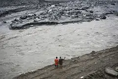 A couple stands along a river in the aftermath of the August 26 flash flood at Betrawoti Bazaar in Nepal's Nuwakot district on September 26, 2026. The August 26 flood, triggered by a glacial mountain collapse near the China-Nepal border, has killed more than 1,400 people, the majority in Nepal.