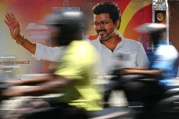 Motorists drive past a poster praising the victory of actor and Tamilaga Vettri Kazhagam (TVK) party president C. Joseph Vijay in Chennai on May 6, 2026. 