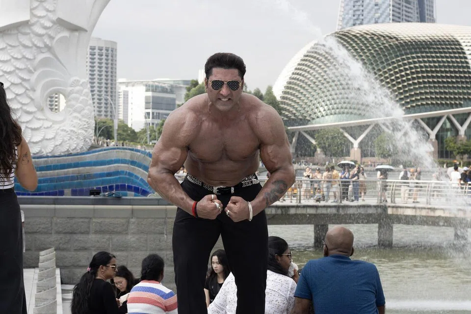 Bodybuilder and actor Varinder Singh Ghuman striking a pose against the backdrop of the Merlion and Esplanade.