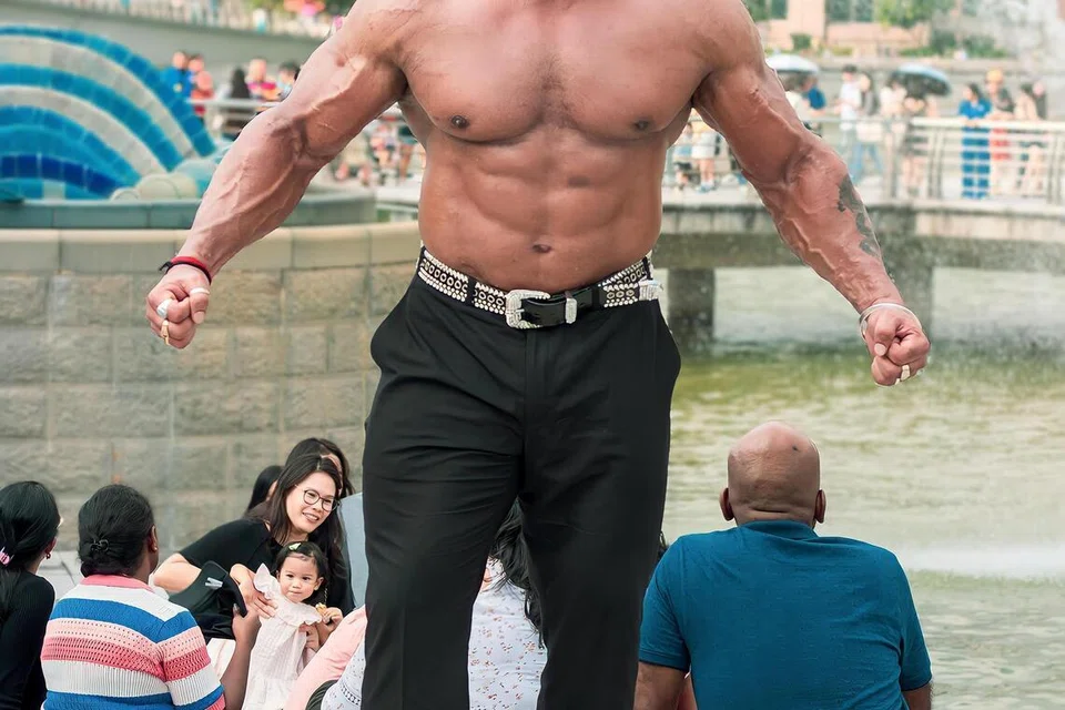 Bodybuilder and actor Varinder Singh Ghuman striking a pose against the backdrop of the Merlion and Esplanade.