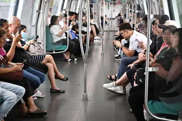 Passengers using their handphones on the train along the East-West Line (EWL) near Tanah Merah MRT station