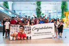 Siddharth Jagadeesh (centre with orchid lei) with his family, friends and members of the Singapore Chess Federation holding up a celebratory banner at Changi Airport.