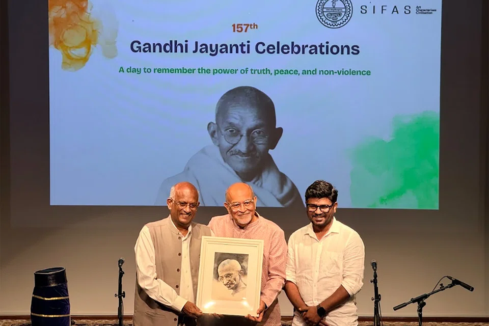 SIFAS president K.V. Rao (left) presenting a painting of Mahatma Gandhi to guest of honour Shabbir Hakimuddin Hassanbhai which was specially created by SIFAS senior tutor Raguveeran Palraj (right).