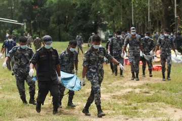 Police officers carry victims who were airlifted from an area affected by flash floods and a mudslide, at the Maithili Barrack, an army training center, in Trishuli, Nuwakot district, Nepal.
