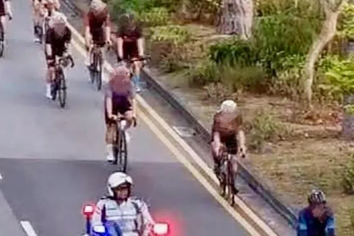 A Traffic Police officer directing a group of cyclists to stop for checks.