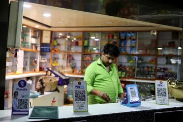 QR codes of digital payment firms PhonePe and Paytm are seen on the counter of a grocery store in Ahmedabad, India
