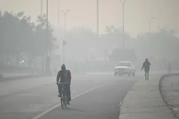 Commuters ride along a street amid dense smog in New Delhi on January 19, 2026.