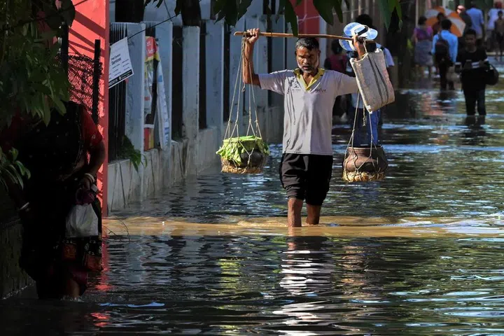 A street vendor wading through a flooded street after heavy rainfall in Guwahati, in India’s state of Assam, on June 26.