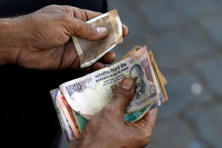A cashier holds Indian currency notes at a fuel station in Ahmedabad