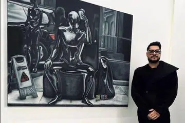 Aryan Arora next to his monochrome painting of an old tissue seller at the MRT station.