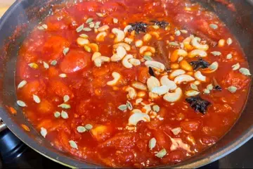 Tomato pachadi with assorted spices, raisins and chopped cashews.