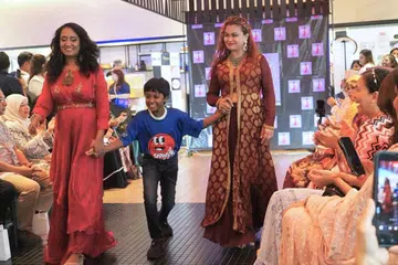 A child with special needs walking hand-in-hand with models at the the charity event “Runway Fashion For A Cause 2026”.
