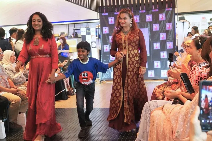 A child with special needs walking hand-in-hand with models at the the charity event “Runway Fashion For A Cause 2026”.