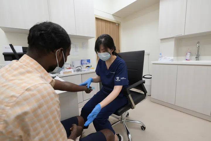 Senior resident physician Ong Hui Yi examining a worker at St Andrew’s Mission Hospital in Penjuru Recreation Centre, 21 September 2023. 