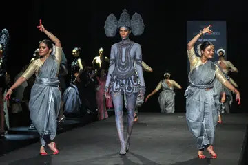 Artistes perform as models present creations by designer Rahul Mishra during the grand finale of the Hyundai India Couture Week 2026.