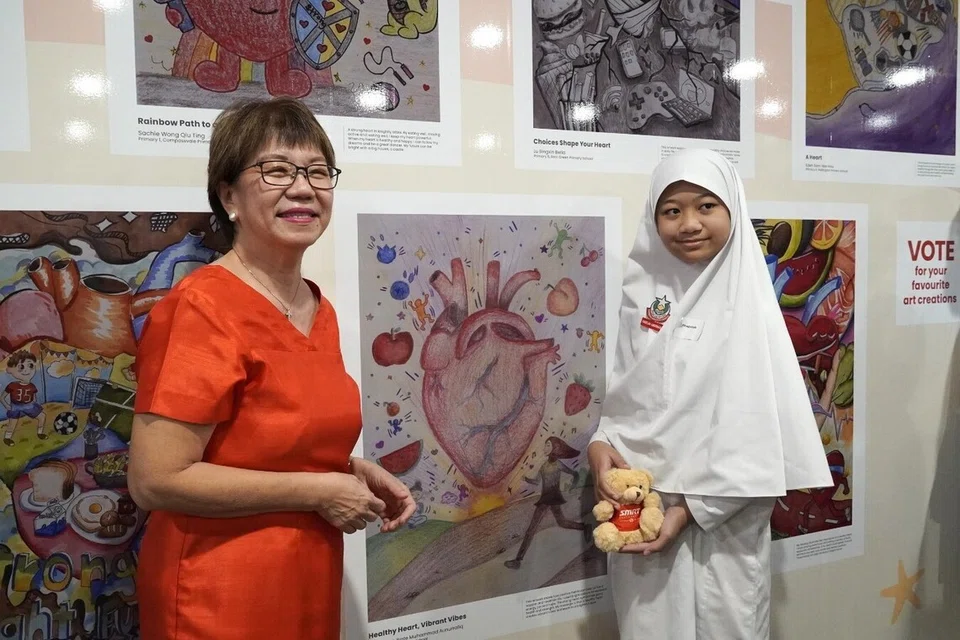 Mayor of Central Singapore and MP for Jalan Besar GRC Denise Phua (far left) and Khadeejah Binte Muhammad Anurrafiq pose with her shortlisted artwork at Bayfront MRT.