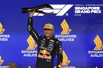 Red Bull's Max Verstappen celebrates with a trophy on the podium after winning the Singapore Grand Prix.