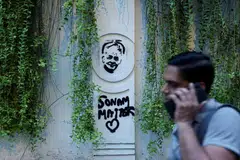 A supporter of India's Cockroach Janata Party (CJP) walks past a graffitti of Sonam Wangchuk at the ongoing protest site, a few days after thousands of protesters marched towards parliament demanding the resignation of Education Minister Dharmendra Pradhan