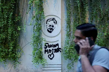 A supporter of India's Cockroach Janata Party (CJP) walks past a graffitti of Sonam Wangchuk at the ongoing protest site, a few days after thousands of protesters marched towards parliament demanding the resignation of Education Minister Dharmendra Pradhan