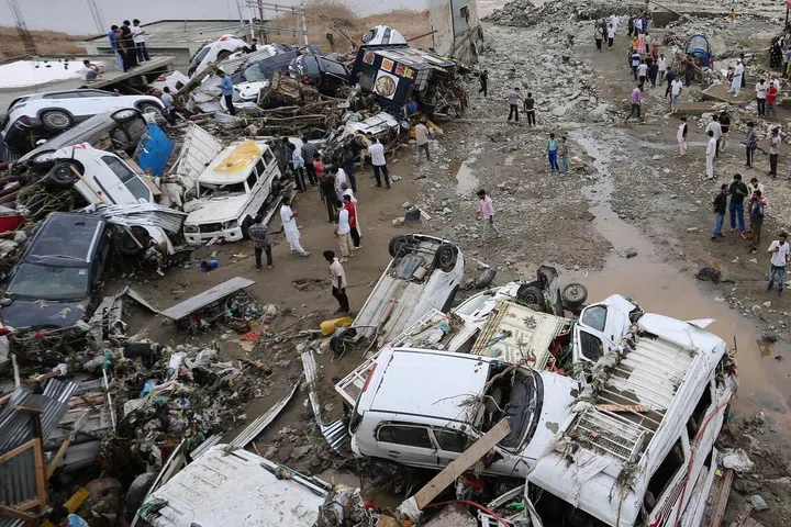 Residents look at damaged vehicles after flash flood and landslide triggered by heavy rains wreaked havoc at Rajouri district in India's Jammu region