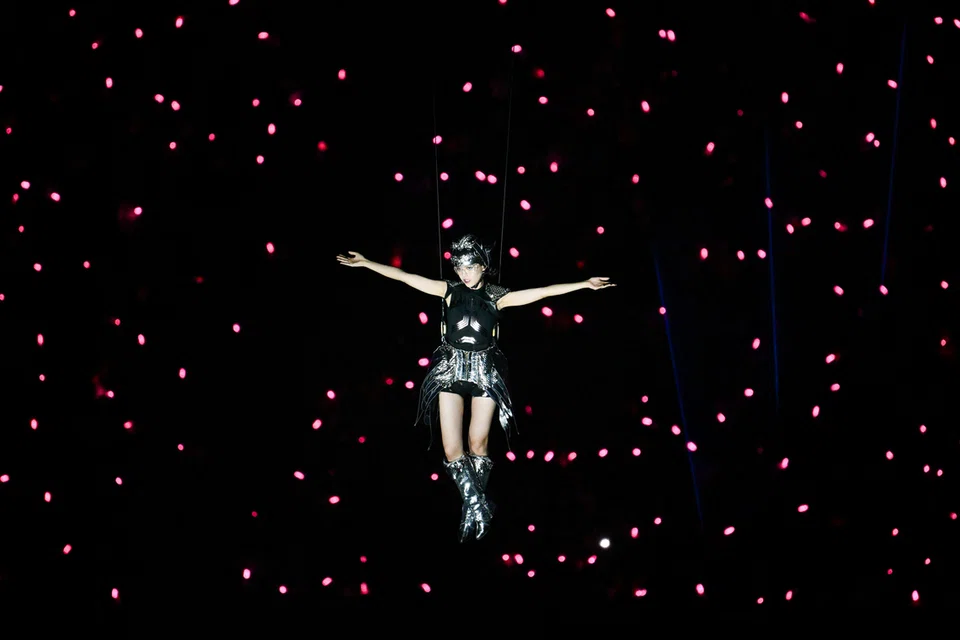 An aerialist descends from the massive cuboid screens as 300 drones light up the stage.