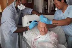 An elderly man getting a free haircut from employees of Indian Barber Shop, helmed by Mr Veerappan Muthukumaran .