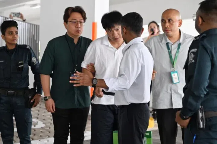 Kong Qi Cong (centre) being escorted by auxiliary police officers and HSA investigation officers to a multi-storey carpark at Block 226D Compassvale Walk on June 30. He is accused of being in possession of Kpods.