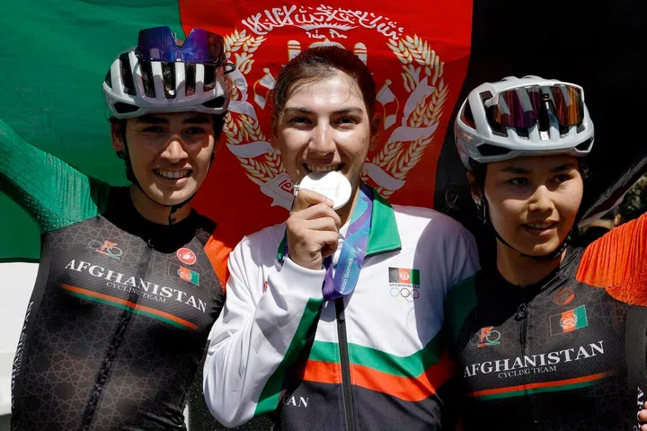 Silver medallist Afghanistan's Fariba Hashimi (centre) celebrates with teammates Yuldoz Hashimi and Zahra Rezayee during the victory ceremony