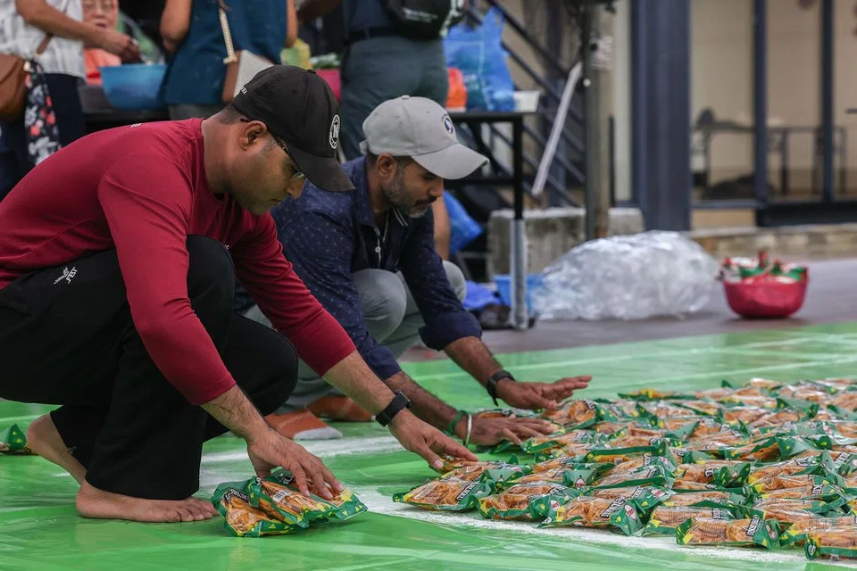 Migrant workers and volunteers arranging packets of murukku for the rangoli.