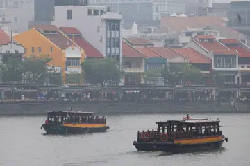 Tourist-oriented bumboats move through the Singapore River, past restaurants at Boat Quay, in haze-shrouded Singapore, October 16, 2026.