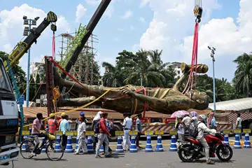 Pedestrians watch as workers remove the statue of Argentinian football player Lionel Messi in Kolkata on June 1.