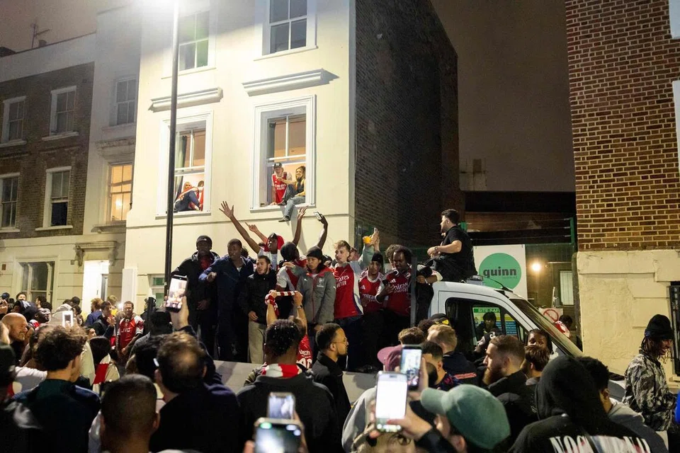 Arsenal fans celebrate their team winning the English Premier League, outside the Emirates Stadium in London on May 20.